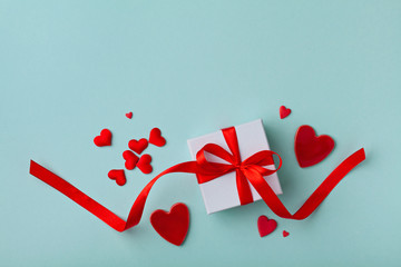 Valentines day background. Gift box and mixed hearts on blue top view. Flat lay.
