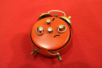 A red antique alarm clock on the reverse side lies on a red background.