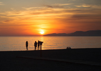 Silhouettes of people on beach at sunset in Spain