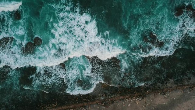 Aerial flight above, turquoise ocean, with the texture of foam on the waves 4k