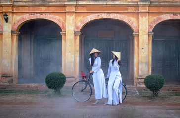Two women wearing the Ao Dai Vietnam traditional dress stay in the ancient village