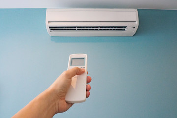 Man pressing button on air conditioner remote control after using to save power and cost. Switching...