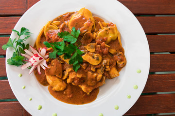 Tortellini, pasta, with mushrooms and tomato sauce, on white plate