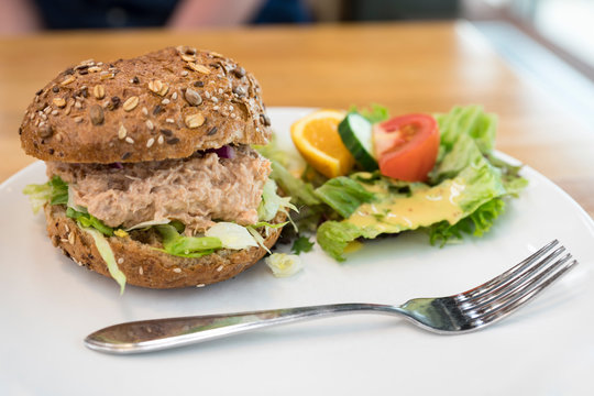 white plate with fork, lettuce and sandwich tuna salad