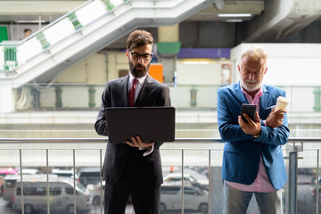 Two multi ethnic bearded businessmen together around the city