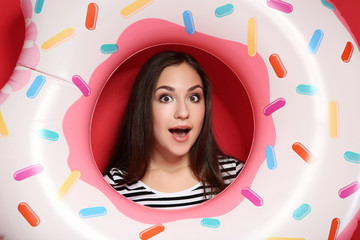 Fototapeta premium Young girl with inflatable donut on red background