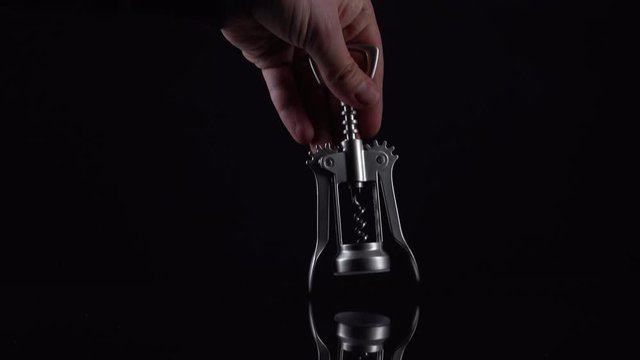 Silver colored bottle opener on black background. Universal shiny corkscrew tool with spiral for opening beverage drinks isolated on dark backdrop with space for text