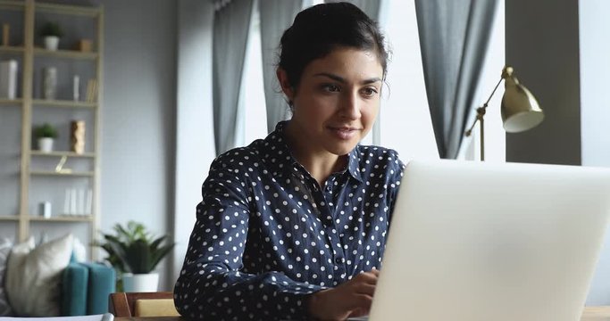 Young successful indian woman celebrate victory triumph looking at laptop