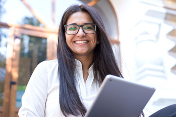 portrait of a beautiful indian girl. Business woman, wearing glasses, smiling, sitting on the steps...