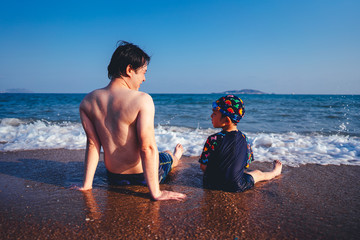 Father and son on the beach during sunset