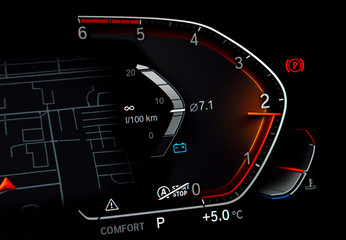 Close up of car tachometer displaying almost 2000 RPM. Modern fully digital vehicle dashboard with average fuel consumption and temperature gauge. Luxury business car cluster with rev counter at night