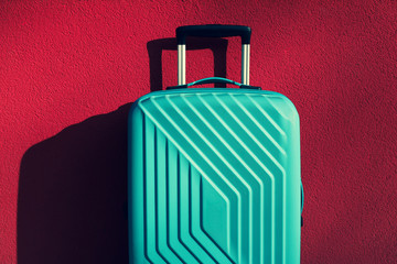 Green travel bag on a red wall background.