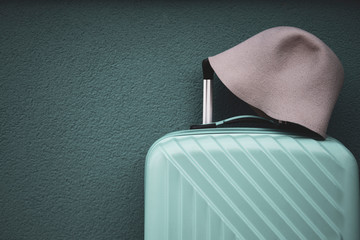 Green travel bag and hat on green wall background; travel and object concept.