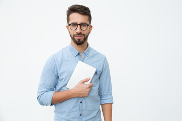 Man holding digital tablet and smiling at camera. Front view of handsome happy young man holding...