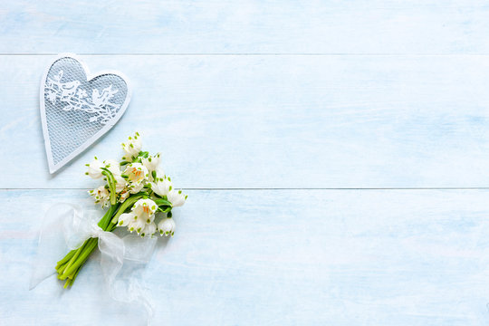 Pattern of lily of snowdrops fiowers  and white hearts shape figurine on a blue sky background. Concept for Valentine's Day and other spring holidays. Greeting card, wedding or engagement invitation