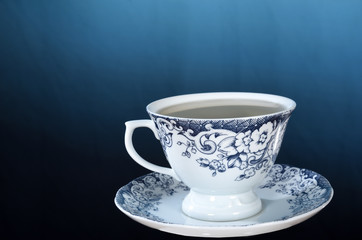 wooden table with cup of tea with rosemary branches isolated on blue gradient background with space for text.
