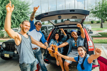 Friends drinking and having fun at tailgate party in sunshine. 