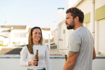 Joyful friends drinking beer on balcony. Cheerful young people laughing while drinking beer during sunny day. Celebration concept