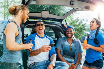 Friends drinking and having fun at tailgate party in sunshine. 