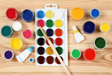 Colorful gouache paints and brush on brown wooden table