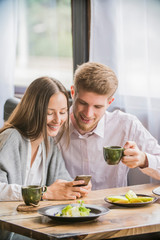 couple in a cafe smiling looking at the phone