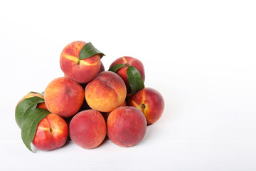 Fototapeta na wymiar Fresh peaches with green leafs on white wooden table