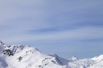 High mountains with snowy peak and sunlit cloudy sky at winter morning