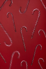 Falling candy canes on red background. Candies levitation christmas trendy pattern