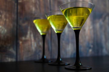 three yellow cocktails glasses in line
