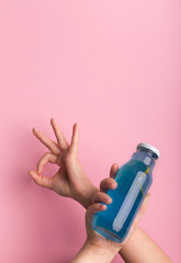Female holding bottle with blue isodrink water and showing ok sign