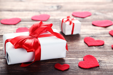 Gift boxes with ribbons and hearts on brown wooden table