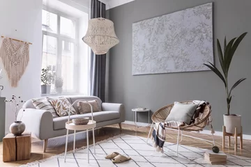 Fotobehang Boho Modern boho interior design of living room with design rattan armchair, gray sofa, coffee table, beige macrame, plants and elegant accessories. Stylish home decor. Abstract paintings. Template.  © FollowTheFlow