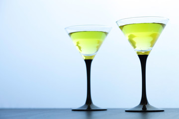 two yellow cocktails glasses on white
