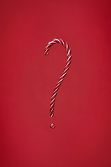 Candy cane question mark on red background. Christmas striped candie