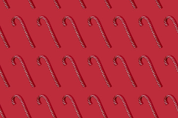 Striped red and white candy canes on red background. Trendy seamless pattern. Flat lay witn Cristmas lollipop hard light