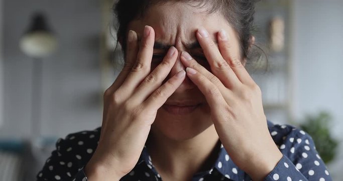 Frustrated stressed young indian woman coping with headache migraine, closeup
