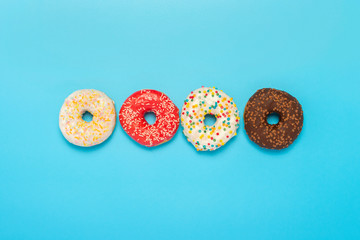 Donuts of different types on a blue background. Concept of sweets, bakery,. Banner. Flat lay, top view