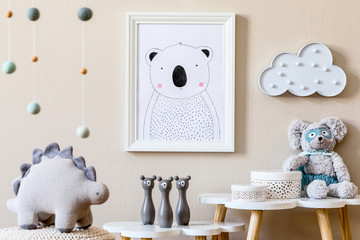 Stylish scandinavian nursery interior with mock up photo frame, plush dino, design furniture, toys and accessories. Beautiful decoration on the beige background wall. Home decor for children room.