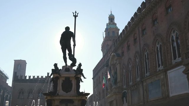 Bologna local landmark of Emilia Romagna region of Italy - fountain of Neptune statue or Fontana del Nettuno and City Hall building in backlight haze