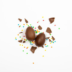 Easter chocolate eggs and colorful decorations on a light background. Easter concept, easter treats. Square. Flat lay, top view