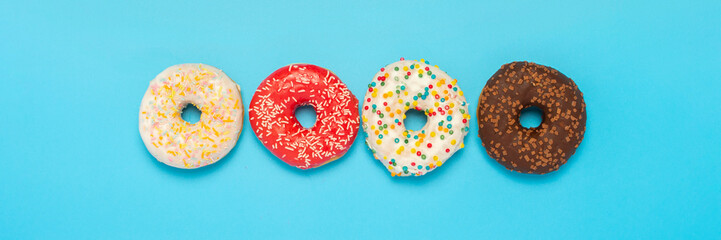 Tasty donuts of different types on a blue background. Concept of sweets, bakery, pastries. Banner. Flat lay, top view