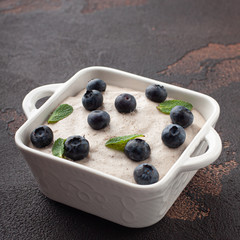 Tasty pudding with blueberry and mint in ceramic square plate. Dark. Top view.