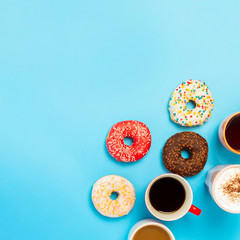Tasty donuts and cups with hot drinks, coffee, cappuccino, tea on a blue background. Concept of sweets, bakery, pastries, coffee shop, meeting, friends, friendly team. square. Flat lay, top view