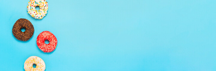 Tasty donuts of different types on a blue background. Concept of sweets, bakery, pastries. Banner. Flat lay, top view