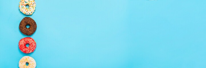 Tasty donuts of different types on a blue background. Concept of sweets, bakery, pastries. Banner. Flat lay, top view