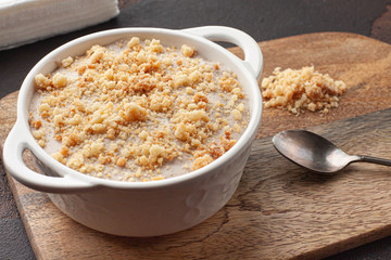 Tasty homemade pudding with crumble cookie in ceramic plate on wooden background.