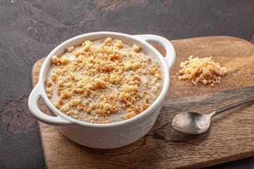 Tasty homemade pudding with crumble cookie in ceramic plate on wooden background.