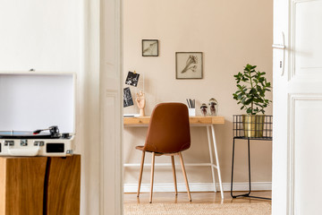 Design scandinavian interior of home office space with a lot of mock up photo frames, wooden desk, brown chair, plants, office and personal accessories.  Stylish neutral home staging. Template.