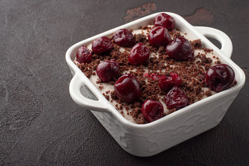 Tasty homemade pudding with chocolate crumble cookie and cherry in square ceramic plate.