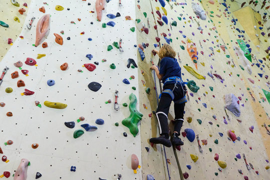 Teenage boy climbing wall in bouldering gym